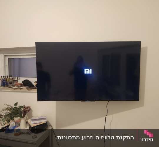 טלוויזיה מותקנת על קיר עם חוט חשמל גלוי